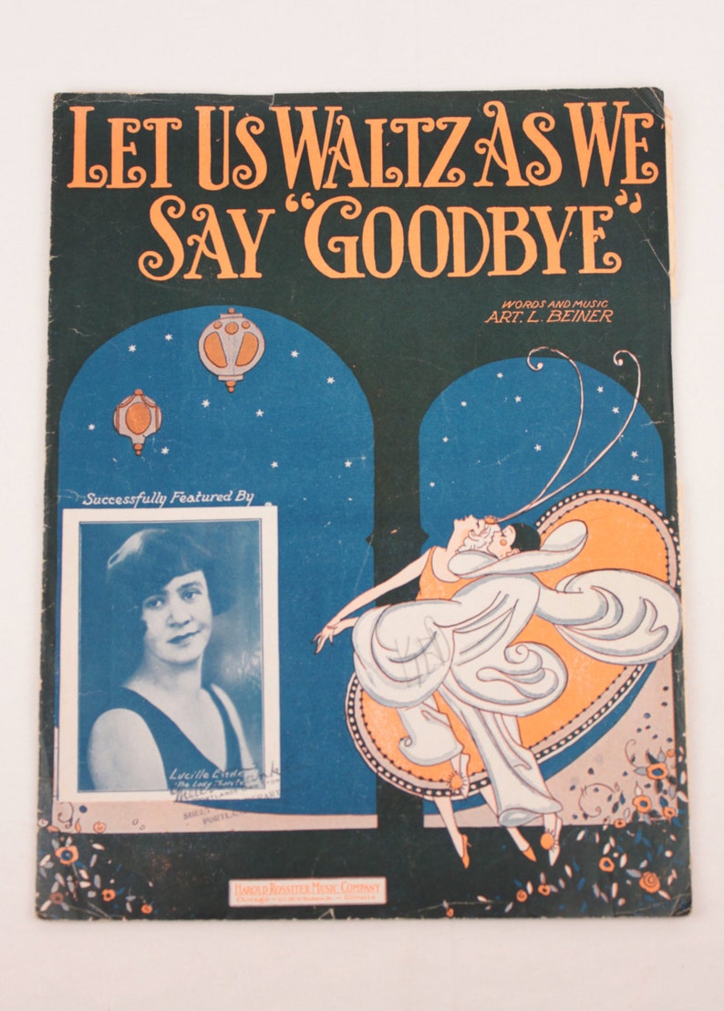 May include: A vintage sheet music cover with a dark green background and a title that reads "Let Us Waltz As We Say 'Goodbye'" in orange lettering. The cover features a couple dancing in a stylized art deco design with a blue and orange background. The music is by Art L. Beiner and features Lucille Cinde.