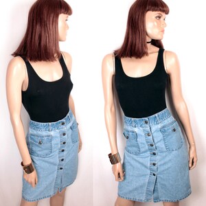 May include: A light blue denim skirt with a button front closure and two large pockets. The skirt is knee-length and has a straight silhouette.