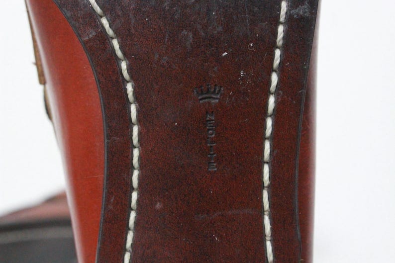 May include: Close-up of the bottom of a brown leather shoe with white stitching around the edge. The shoe has a crown logo and the text "NEOLITE" embossed on the leather.