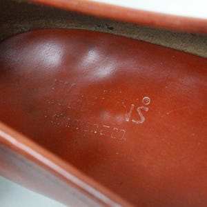 May include: Close-up of the inside of a brown leather shoe with the text "The Shoe's" printed on the insole.
