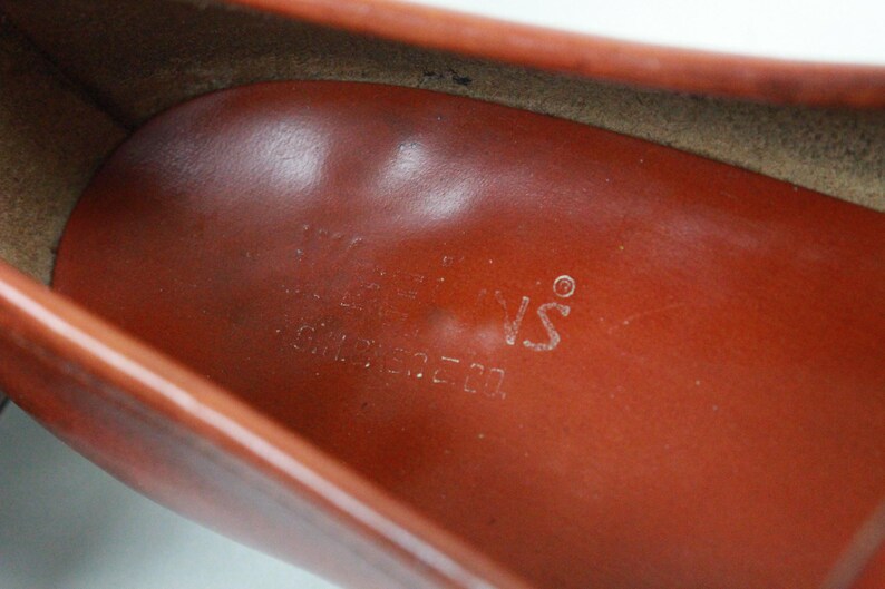 May include: Close-up of the inside of a brown leather shoe with the text "The Shoe's" printed on the insole.