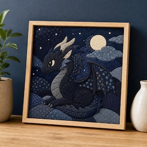 Op de afbeelding: Een vierkant ingelijst stoffen kunstwerk met een donkerblauwe draak met lichtgrijze hoorns en accenten. De draak is geplaatst tegen een nachtelijke hemel met een crèmekleurige maan, kleine witte sterren en gelaagde blauwe stoffen wolken met patronen.