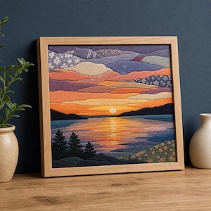 Könnte beinhalten: Ein quadratisches Wandbild aus Stoff in einem hellen Holzrahmen, das einen Sonnenuntergang über einem See darstellt. Die Szene besteht aus geschichteten Textilstücken in Lila-, Orange- und Blautönen mit einer hellen Sonne, die sich im Wasser spiegelt.