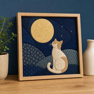 Peut inclure: Une œuvre d'art murale en tissu encadrée de forme carrée représentant un collage textile superposé d'un chat assis regardant une grande lune jaune. Le fond se compose de sections de tissu bleu foncé avec divers motifs, dont des fleurs blanches.