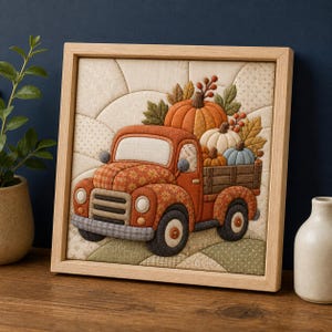 Könnte beinhalten: Ein quadratisches Wandbild aus Stoff in einem Holzrahmen, das einen gesteppten orangefarbenen Lastwagen mit Kürbissen und Herbstblättern zeigt. Der Lastwagen hat ein Blumenmuster, eine graue Stoßstange und schwarze Räder auf cremefarbenem Grund.