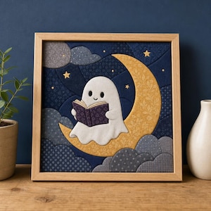 May include: A square fabric wall art piece in a light wood frame featuring a white ghost sitting on a yellow crescent moon. The ghost holds a dark purple book. The background consists of dark blue fabric patches with gray clouds and small gold stars.