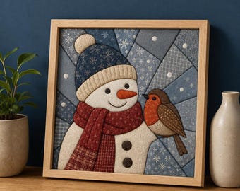 Puede incluir: Un cuadro de pared de tela enmarcado de forma cuadrada que muestra un muñeco de nieve con un gorro de punto azul oscuro y una bufanda roja estampada, con una nariz de zanahoria naranja y dos botones oscuros. Un pequeño petirrojo marrón se posa.