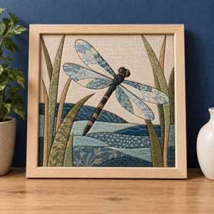 Könnte beinhalten: Ein quadratisches, gerahmtes Stoffkunstwerk mit einer zentralen Libelle mit blau gemusterten Flügeln und einem dunklen, segmentierten Körper. Die Libelle ist über stilisierten blauen Wasserwellen positioniert und von hohen grünen Grashalmen auf beigem Grund umgeben.