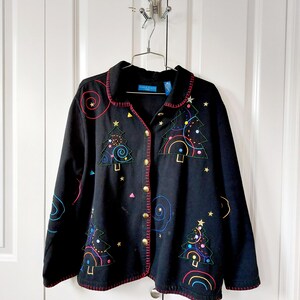 May include: Black button-down jacket with colorful embroidered Christmas tree designs. The jacket features gold buttons and red stitching along the edges. The design includes stars, rainbows, and spiral accents, creating a festive holiday theme.