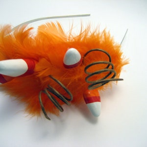 May include: Orange feather headband with white and orange candy corn decorations and a brown spring.