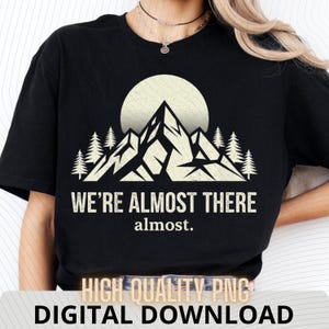 Könnte beinhalten: Schwarzes T-Shirt mit einem Berg- und Sonnengrafik. Unter der Grafik steht in weißer Schrift "WE'RE ALMOST THERE" und "almost.". Die Worte "HIGH QUALITY PNG" und "DIGITAL DOWNLOAD" sind unten aufgedruckt.