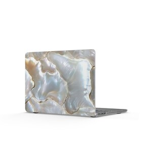 May include: A laptop computer featuring a protective skin with a glossy, iridescent mother-of-pearl pattern. The surface displays organic, flowing shapes in shades of white, cream, and soft gray with a shimmering, pearlescent finish throughout.