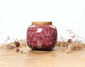 Puede incluir: Un tarro de cerámica redondo con un acabado de esmalte moteado en color magenta intenso y morado oscuro. El recipiente cuenta con una tapa de madera circular, plana y lisa, que encaja perfectamente en la abertura superior. Cuerpo ancho y abombado.