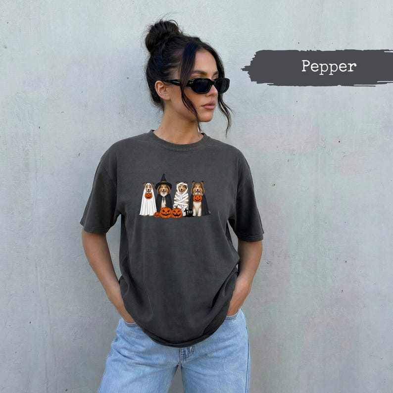 T-shirt with graphic of dogs in Halloween costumes and pumpkins.