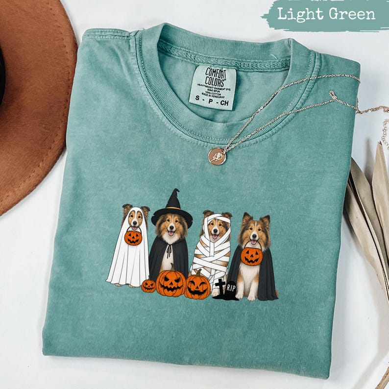 Light green t-shirt with cartoon dogs dressed for Halloween.