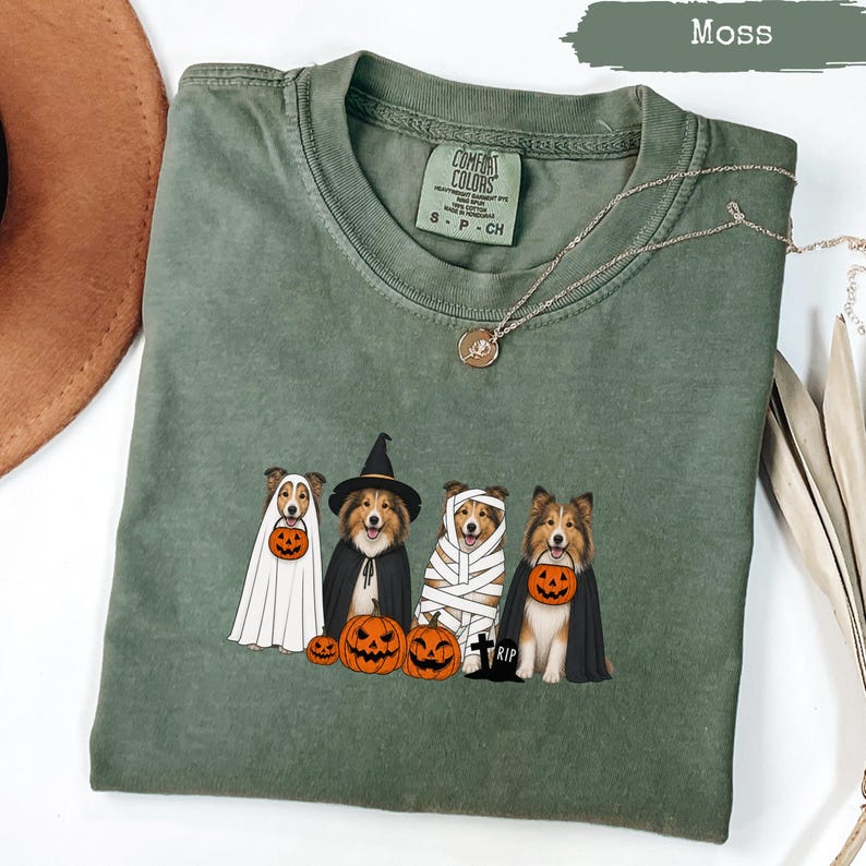 Green t-shirt with four dogs in Halloween costumes and pumpkins.