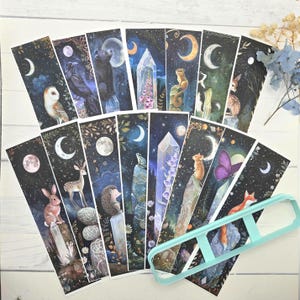 May include: A collection of rectangular bookmarks featuring dark, celestial night sky illustrations with moons, stars, crystals, and various animals including owls, bears, deer, hedgehogs, and foxes, accompanied by a light blue plastic bookmark mold.