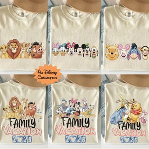 以下が含まれることがあります： 様々なディズニーキャラクターのデザインが施された、クリーム色のTシャツ。ライオンキング、ミッキーマウス、くまのプーさんのキャラクターが描かれています。一部のシャツには「Family Vacation 2026」の文字が入っています。