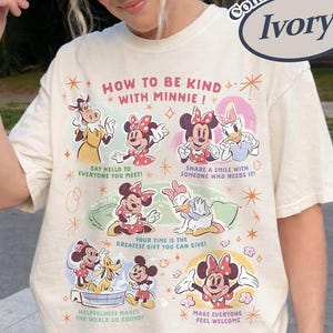 Puede incluir: Camiseta Comfort Colors color marfil con Minnie Mouse y sus amigos. La camiseta tiene el texto "HOW TO BE KIND WITH MINNIE!" y varios consejos de amabilidad. El gr&aacute;fico incluye im&aacute;genes de dibujos animados de Minnie, Daisy y otros personajes de Disney.