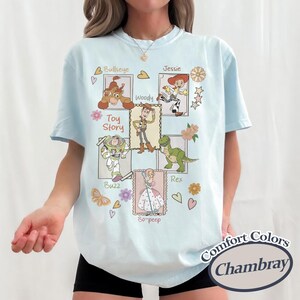 Puede incluir: Camiseta azul claro con un gr&aacute;fico de los personajes de Toy Story: Bullseye, Woody, Jessie, Buzz, Rex y Bo-Peep. La camiseta incluye el texto "Toy Story" y "Comfort Colors Chambray".