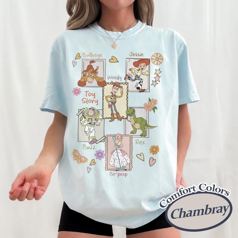 Puede incluir: Camiseta azul claro con un gr&aacute;fico de los personajes de Toy Story: Bullseye, Woody, Jessie, Buzz, Rex y Bo-Peep. La camiseta incluye el texto "Toy Story" y "Comfort Colors Chambray".