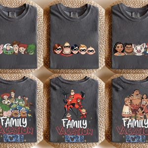 以下が含まれることがあります： さまざまな漫画のキャラクターデザインが施された、6枚のチャコールグレーのTシャツ。シャツには、トイ・ストーリー、インクレディブル、モアナのキャラクターが登場します。各シャツには、白と赤で「Family Vacation 2026」と書かれています。