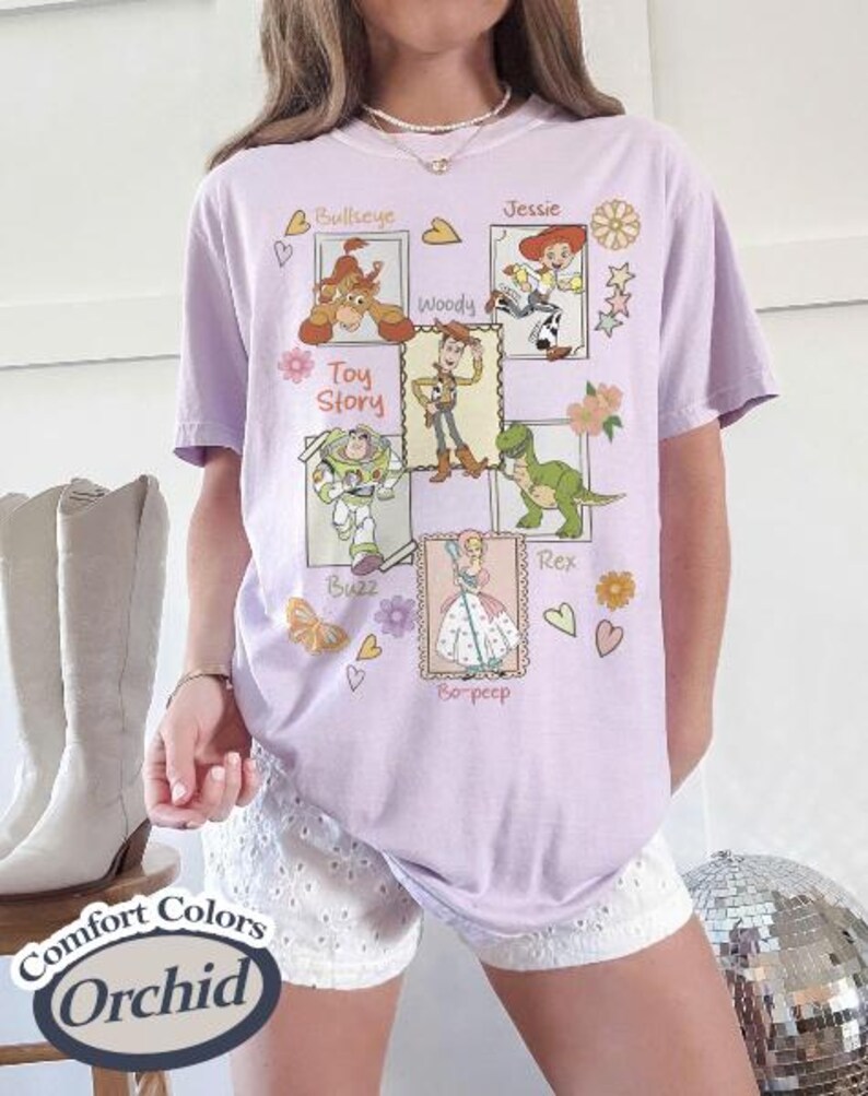 Puede incluir: Una camiseta de color lila claro con ilustraciones de personajes de la pel&iacute;cula "Toy Story". El dise&ntilde;o incluye a Bullseye, Woody, Buzz, Rex, Jessie y Bo-Peep. Las palabras "Toy Story" est&aacute;n impresas en la camiseta.