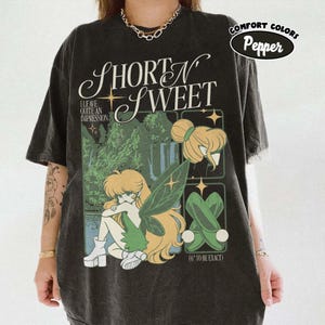 Puede incluir: Camiseta negra con una ilustraci&oacute;n caprichosa de un hada con cabello rubio y alas verdes. La camiseta tiene el texto "Short N Sweet", "I leave quite an impression" y "(6" to be exact)". La camiseta tambi&eacute;n tiene el texto "Comfort Colors Pepper".