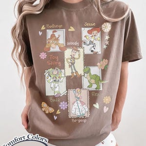 Puede incluir: Camiseta marr&oacute;n con un dise&ntilde;o de los personajes de Toy Story: Bullseye, Woody, Jessie, Buzz, Rex y Bo-peep. La camiseta incluye el texto "Toy Story" y "Comfort Colors".