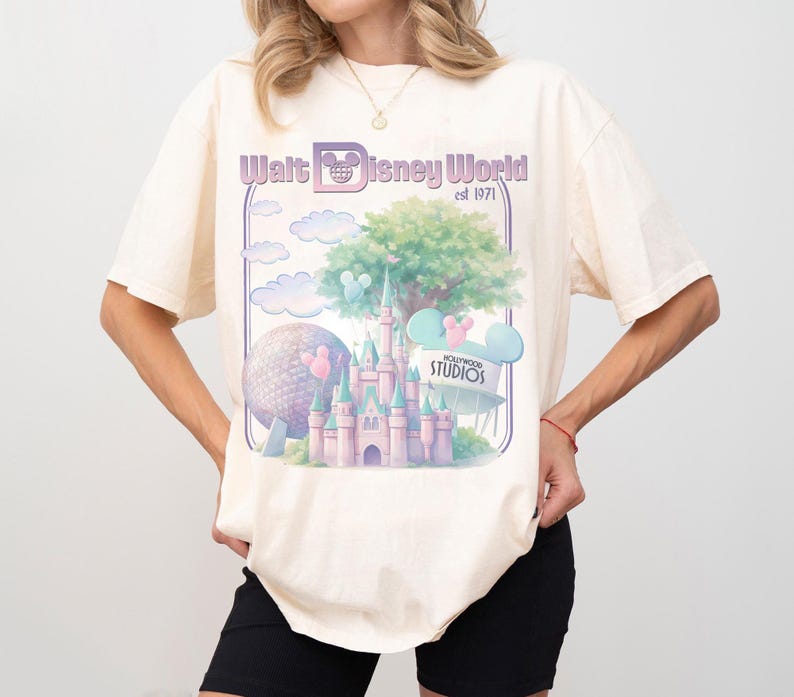 Puede incluir: Camiseta color crema con un gr&aacute;fico de Walt Disney World est. 1971. El dise&ntilde;o incluye un castillo, Spaceship Earth, nubes y orejas de Mickey Mouse en colores pastel. La camiseta es de corte holgado.