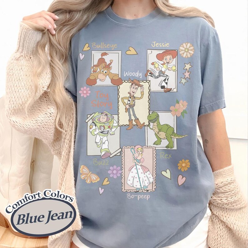 Puede incluir: Camiseta azul vaquero Comfort Colors con ilustraciones de los personajes de Toy Story: Woody, Buzz, Jessie, Rex, Bo-Peep y Bullseye. La camiseta incluye el texto "Toy Story" y los nombres de los personajes.