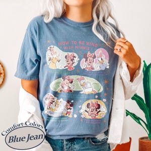 Puede incluir: Camiseta azul vaquero con un gr&aacute;fico de Minnie Mouse y sus amigos. La camiseta tiene el texto "HOW TO BE KIND WITH MINNIE", "HELPFULNESS MAKES THE WORLD GO ROUND!" y "MAKE EVERYONE FEEL WELCOME".