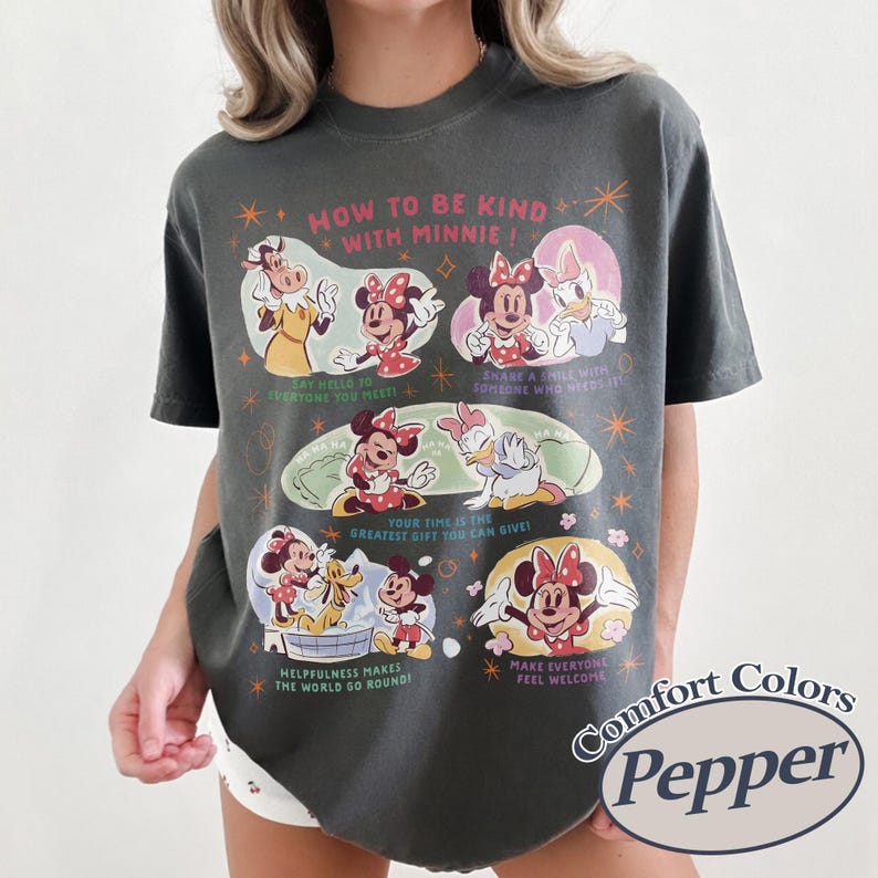 Puede incluir: Camiseta Comfort Colors gris oscuro con Minnie Mouse y sus amigos con el texto "HOW TO BE KIND WITH MINNIE!". El dise&ntilde;o incluye ilustraciones y frases como "Say hello to everyone you meet!" y "Make everyone feel welcome."