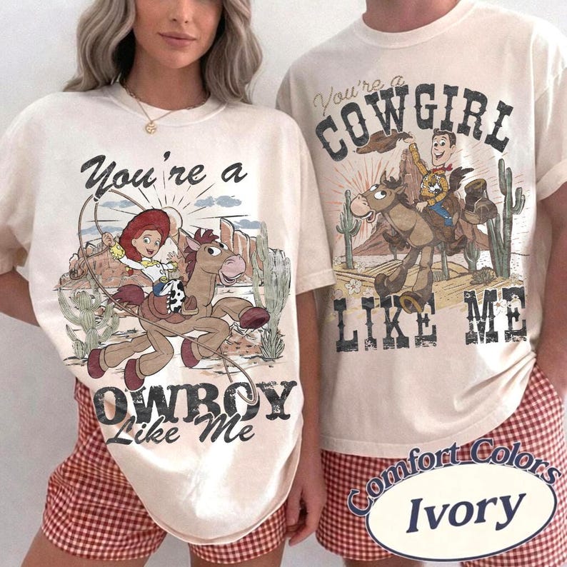 May include: Two ivory-colored t-shirts featuring graphic prints of characters from Toy Story. The left shirt displays Jessie riding a horse with the text You're a COWBOY Like Me. The right shirt shows Woody riding a horse with the text You're a COWGIRL LIKE ME.