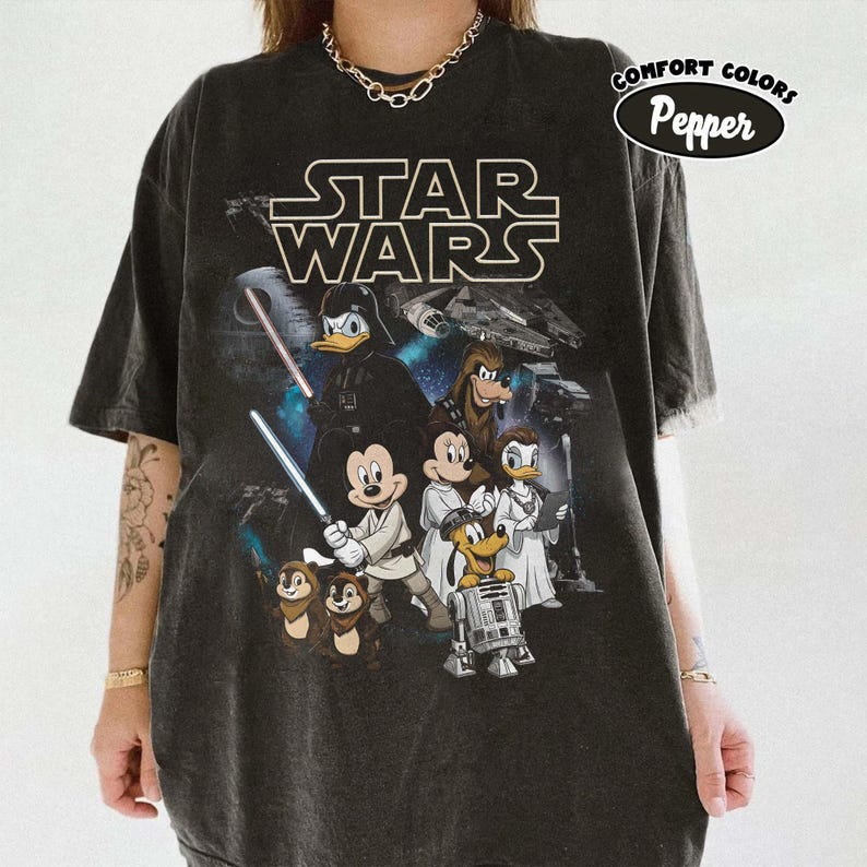 May include: Black t-shirt with a Star Wars graphic featuring Disney characters. The design includes Darth Vader as Donald Duck, Mickey Mouse, and other characters in Star Wars attire. The shirt has a Comfort Colors Pepper label.