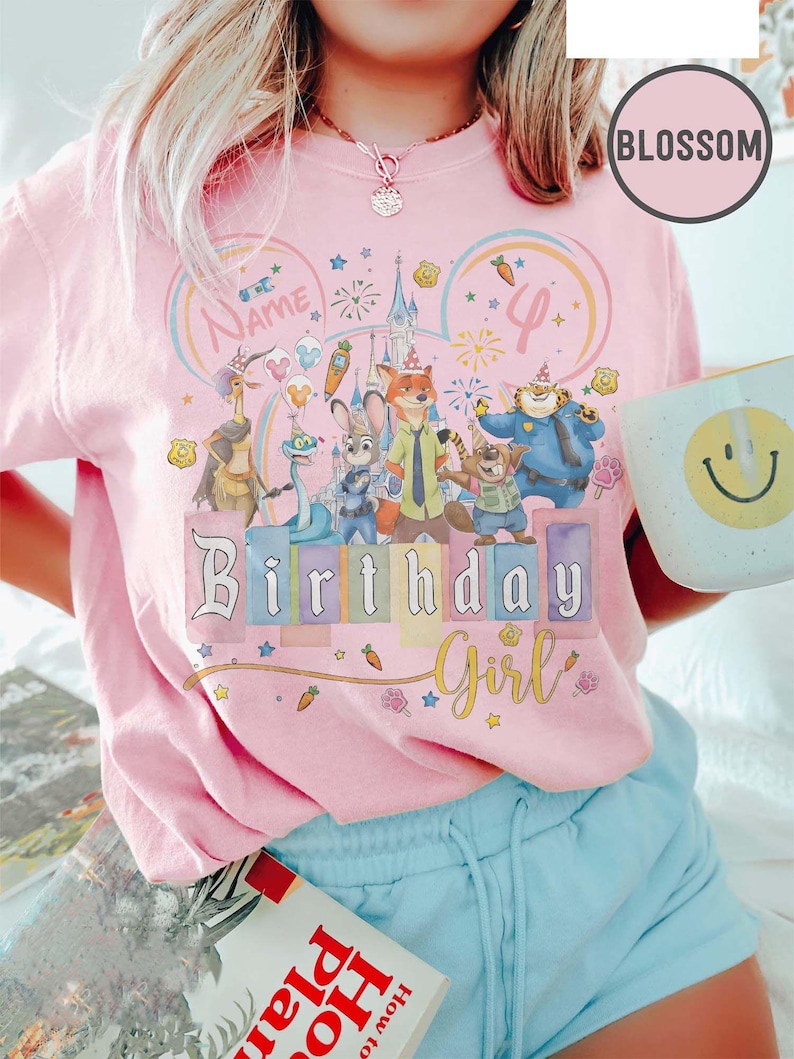 以下が含まれることがあります： 漫画のキャラクター、花火、そして「Birthday Girl」の文字が描かれたカラフルなグラフィックのピンク色のTシャツ。 デザインには数字の「4」と「Name」の文字が含まれています。 その人は水色のショートパンツを履いて、スマイリーフェイスのマグカップを持っています。
