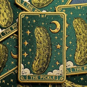 May include: Embroidered patch featuring a pickle tarot card design. The card has a green background with gold stars, a crescent moon, and a pickle illustration. The text "THE PICKLE" is at the bottom.