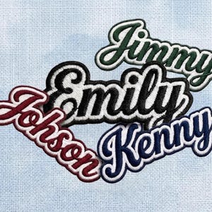 May include: Four embroidered name patches featuring cursive lettering with white borders. The names Jimmy in dark green, Emily in black, Johnson in maroon, and Kenny in navy blue are displayed in a stacked arrangement with stitched edges.