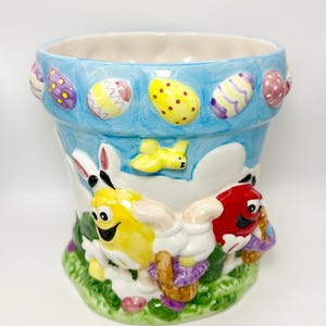 May include: A white ceramic mug with a black handle and the text "But First, Coffee" in a black, bold font. The mug is on a wooden surface. The mug is 10 cm tall.