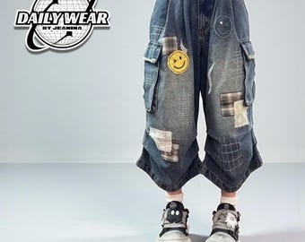 Puede incluir: Pantalones cargo de mezclilla azul con parches y detalles de caritas sonrientes. Los pantalones tienen un diseño de pierna ancha y se combinan con zapatillas deportivas. Se lleva un cinturón a cuadros con personajes de dibujos animados en la cintura. El texto "DAILY WEAR BY JEANINA" es visible.