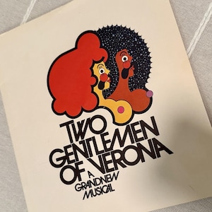 Puede incluir: Un cartel vintage de la obra musical "Two Gentlemen of Verona". La obra de arte presenta dos figuras de dibujos animados estilizadas con pelo naranja y marrón, sobre un fondo azul oscuro. El título está en letras negras en negrita.