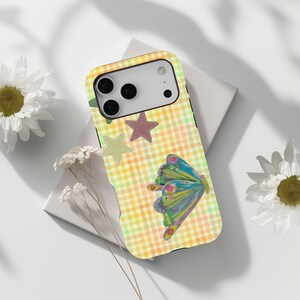 May include: A smartphone case featuring a yellow and orange gingham check pattern. The design includes two five-pointed stars in light green and muted red, along with a colourful butterfly illustration with blue, green, and purple wing patterns.