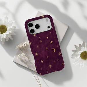 May include: A deep burgundy smartphone case featuring a repeating pattern of gold-coloured stars and a crescent moon. The case has a rectangular cutout for the camera lenses and flash, with a smooth, matte-textured finish across the surface.