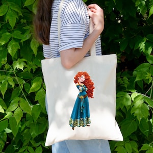 May include: Cream-colored tote bag featuring a cartoon illustration of a character with long, curly red hair and a blue dress. The character is standing with arms crossed. The bag has a simple design with a shoulder strap.