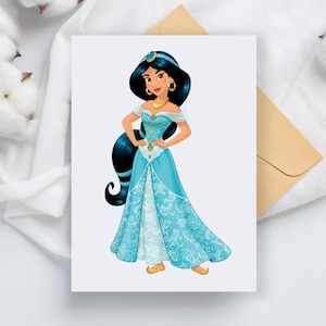 May include: A greeting card featuring a cartoon illustration of a woman in a teal gown with gold jewelry and a matching headband. The card is on a white surface with a brown envelope.