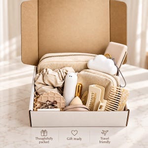 May include: A cardboard gift box containing a beige corduroy pouch, a white cloud-shaped object, a white cat-shaped item, a waffle-textured disc, a beige hair scrunchie, a hair clip, a comb, and a makeup sponge. Text reads: Thoughtfully packed, Gift ready, Travel friendly.