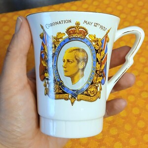 May include: A white ceramic mug commemorating the coronation of King Edward VIII, dated May 12th 1937. The mug features a portrait of the King, royal crests, and flags, with gold trim. A vintage collectable item.