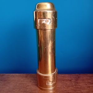 May include: A gold metal bottle stopper with a decorative top and a white plastic ring around the base.