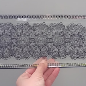 May include: A clear glass serving tray with a black and white geometric design. The design features a repeating pattern of circles and lines.