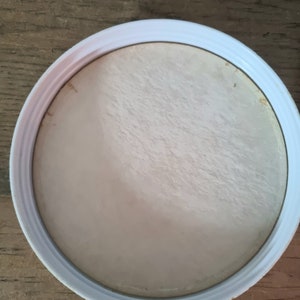 May include: White round lid with a slightly textured surface.